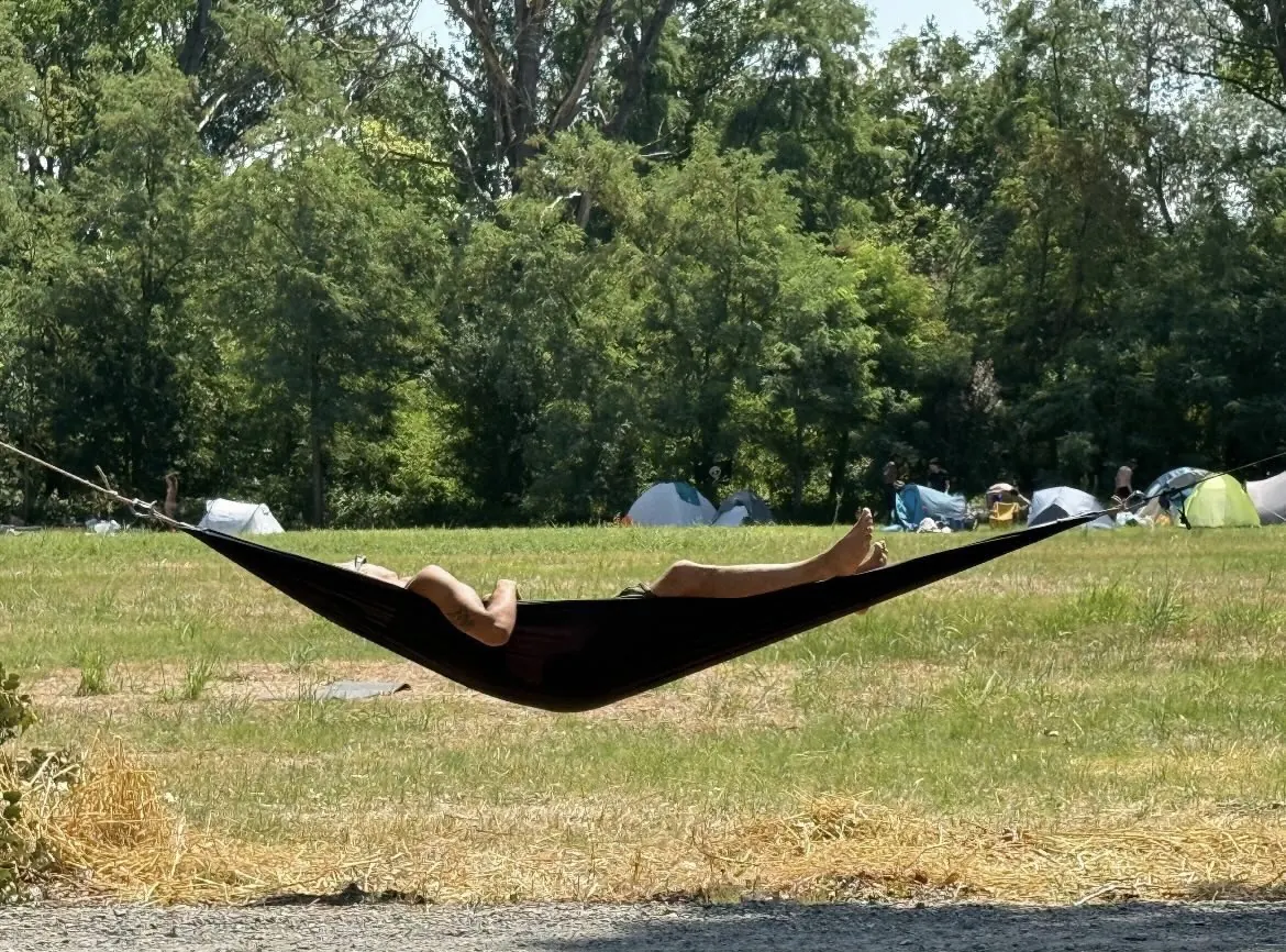 Amaca nera tesa in un campo durante un raduno, tende sullo sfondo