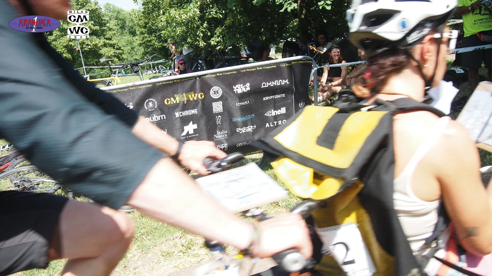 CMWC 2026, Milano — corridori davanti allo striscione degli sponsor con il logo Arahuaca