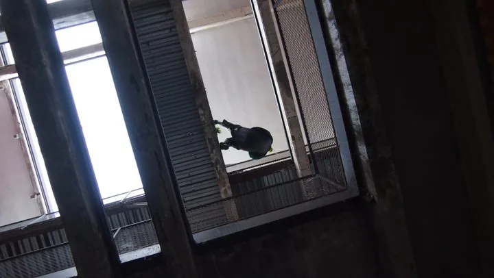Persona affacciata, amaca in una tromba delle scale urbana