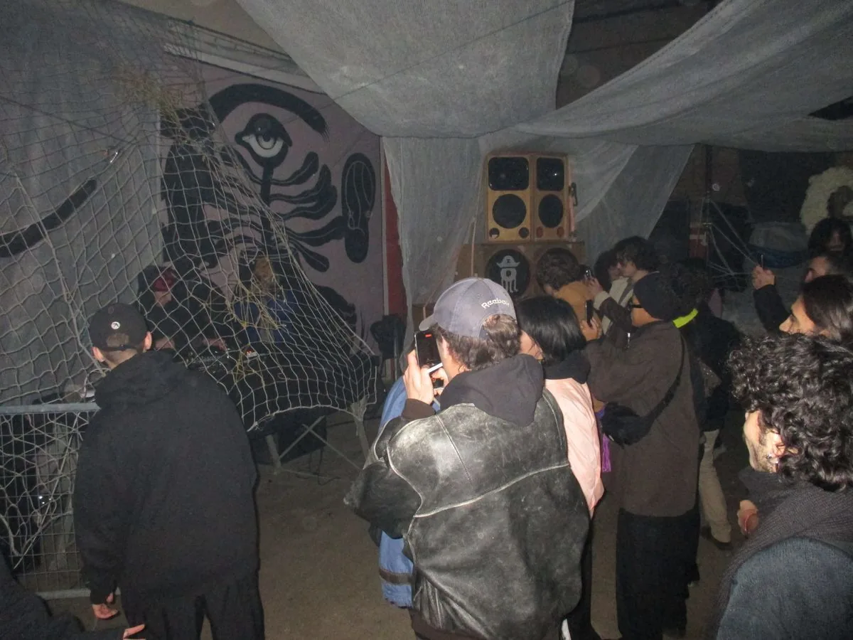 Pubblico tra reti e tendaggi sospesi alla serata Gleba2k, Bologna